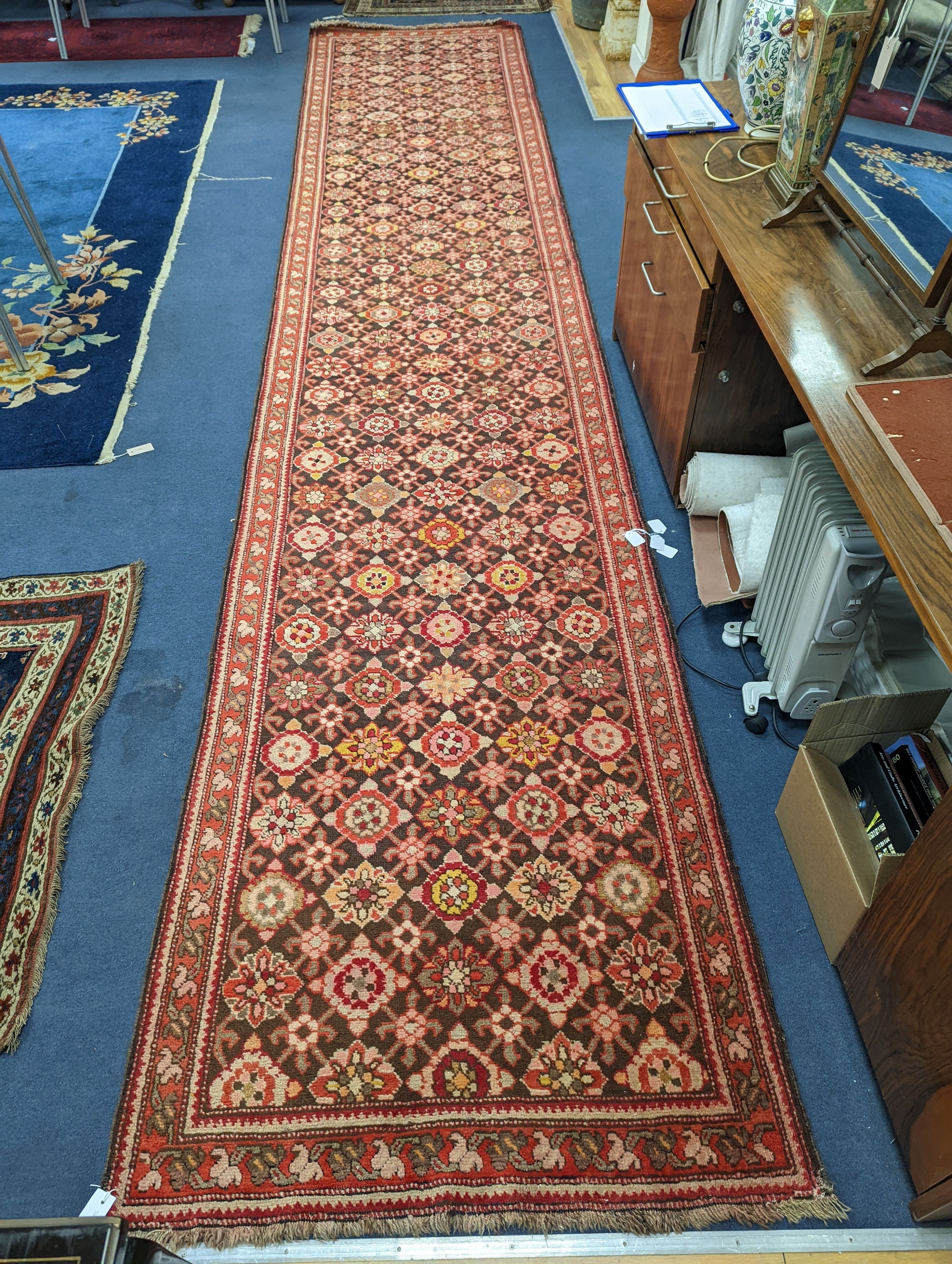 A North West Persian runner woven with rows of floral motifs, 575 x 110cm